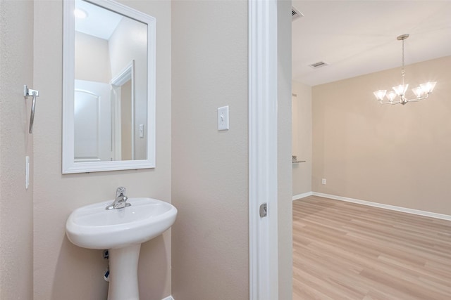 bathroom featuring baseboards, visible vents, wood finished floors, and an inviting chandelier