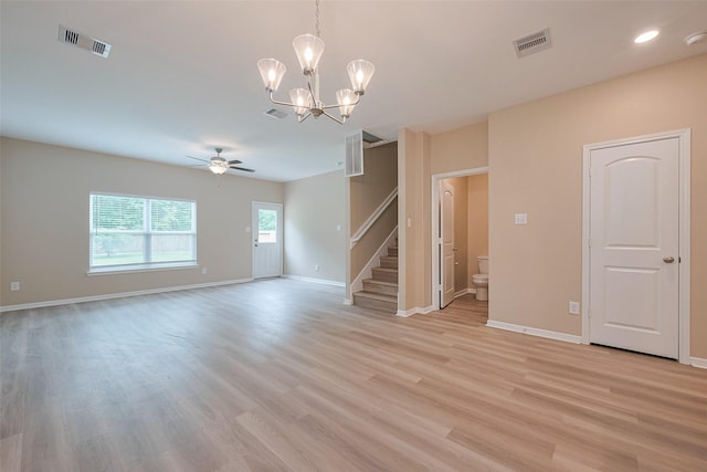 unfurnished living room featuring visible vents, ceiling fan with notable chandelier, light wood finished floors, and stairway