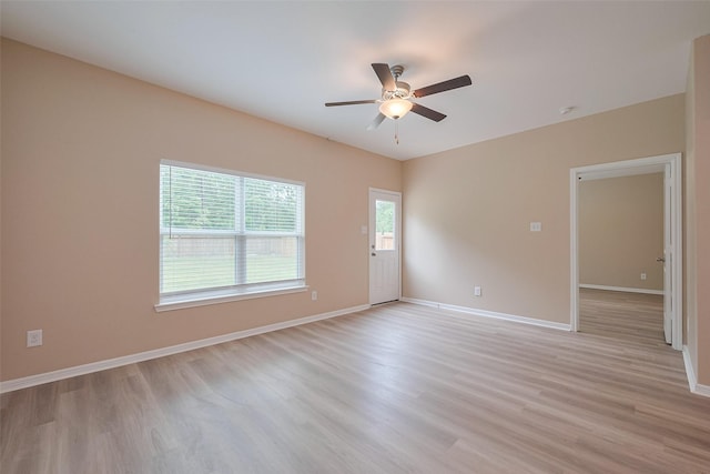 empty room with light wood-style floors, a ceiling fan, and baseboards