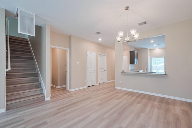 unfurnished living room featuring visible vents, light wood-type flooring, and stairs