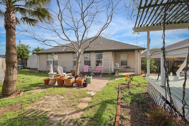 24 Clara Barton Ln, Galveston, TX 77551 - back of property featuring a wooden deck, brick siding, a storage unit, a shingled roof, and an outbuilding