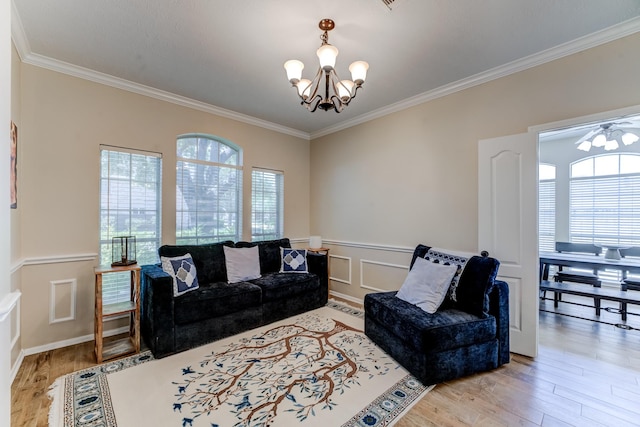 living room featuring a chandelier, a decorative wall, ornamental molding, wainscoting, and wood finished floors