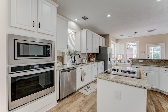 kitchen featuring visible vents, stainless steel appliances, a kitchen island, and a sink