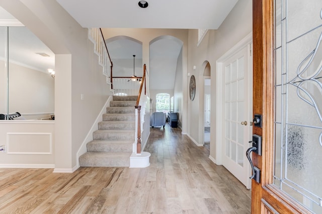 entrance foyer with baseboards, wood finished floors, stairs, and arched walkways