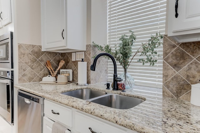 kitchen featuring tasteful backsplash, stainless steel appliances, white cabinets, and a sink