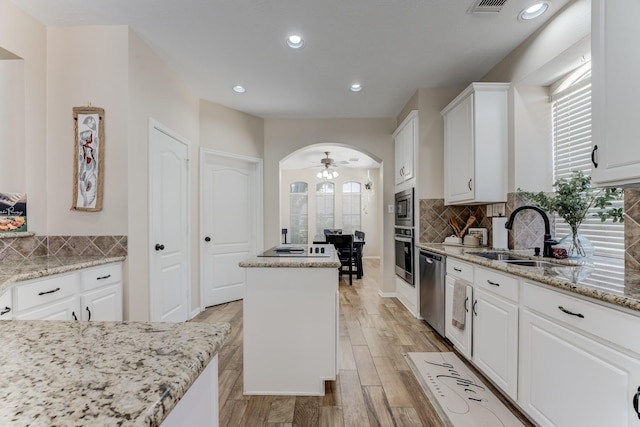kitchen with white cabinetry, appliances with stainless steel finishes, a kitchen island, and a sink