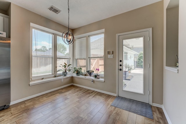 interior space with baseboards, visible vents, wood finished floors, and a notable chandelier