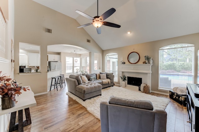 living area featuring a ceiling fan, visible vents, a wealth of natural light, and arched walkways