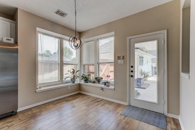 unfurnished dining area featuring baseboards, visible vents, and light wood-style flooring