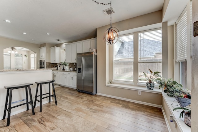 kitchen with stainless steel refrigerator with ice dispenser, visible vents, a healthy amount of sunlight, and decorative backsplash