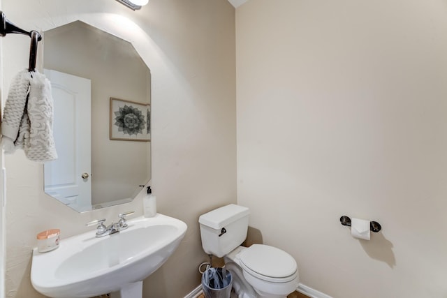 bathroom featuring baseboards, toilet, and a sink
