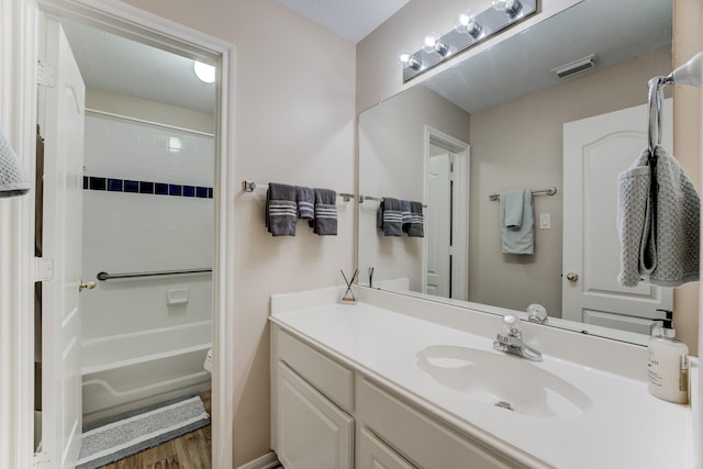 bathroom featuring visible vents, shower / bathtub combination, toilet, wood finished floors, and vanity