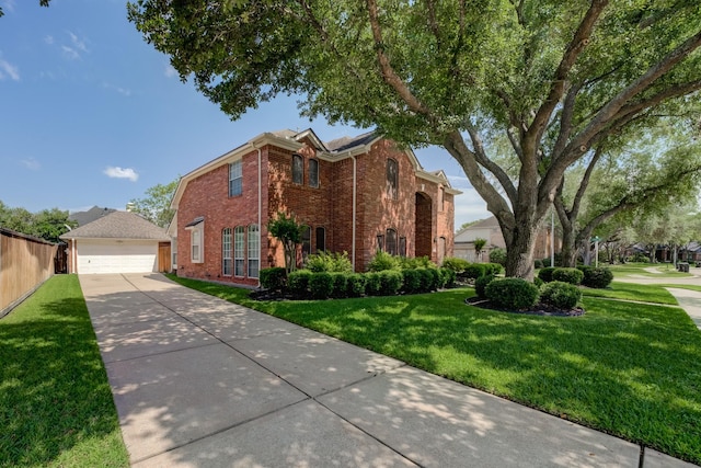 traditional home with an outdoor structure, a detached garage, a front yard, and brick siding