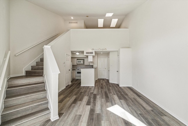 10855 Meadowglen Ln Unit 1030, Houston, TX 77042 - unfurnished living room featuring high vaulted ceiling, stairs, visible vents, a skylight, and dark wood finished floors