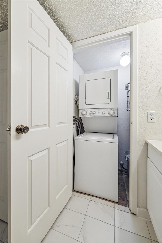 10855 Meadowglen Ln Unit 1030, Houston, TX 77042 - laundry area featuring a textured ceiling, stacked washer / drying machine, laundry area, and marble finish floor