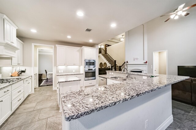 5722 Willow Park Terrace Ln, Porter, TX 77365 - kitchen featuring appliances with stainless steel finishes, a large island with sink, a sink, ceiling fan, and decorative backsplash