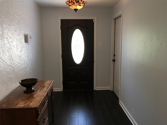 entrance foyer with baseboards, a textured wall, and dark wood-style floors