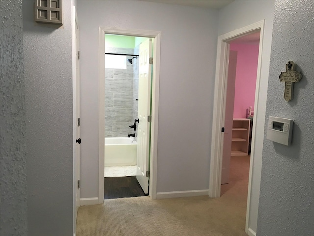 hallway with carpet floors and baseboards