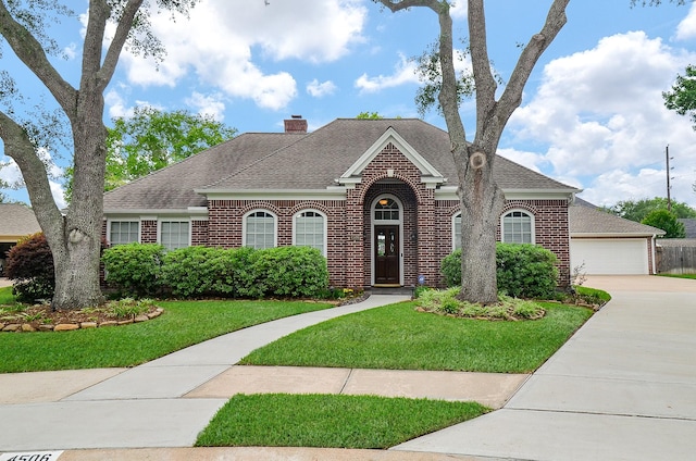 view of front of property featuring a front lawn, a garage, brick siding, a chimney, and roof with shingles