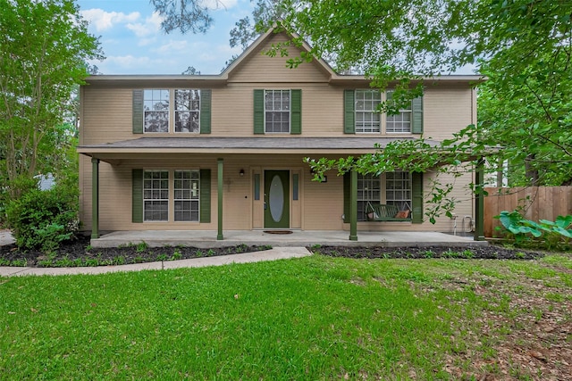 traditional-style house with covered porch, fence, and a front yard