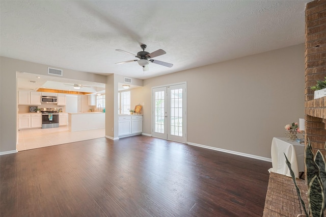 unfurnished living room with wood-type flooring, a ceiling fan, visible vents, and baseboards