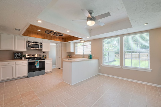 kitchen featuring stainless steel appliances, a raised ceiling, visible vents, light countertops, and a textured ceiling