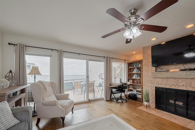 living area with light wood-type flooring, a ceiling fan, recessed lighting, and a fireplace