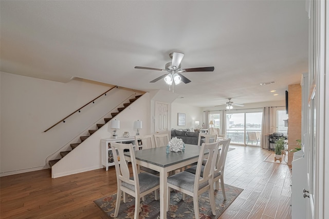 dining space with ceiling fan, wood-type flooring, baseboards, visible vents, and stairway