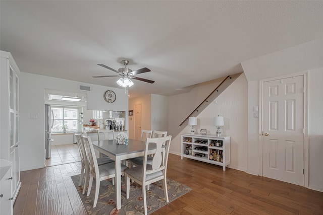 dining space featuring ceiling fan, visible vents, stairway, and hardwood / wood-style floors