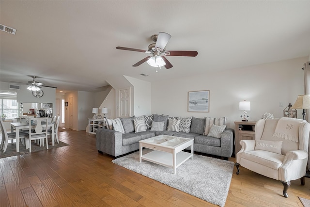 living area featuring ceiling fan, visible vents, and wood finished floors