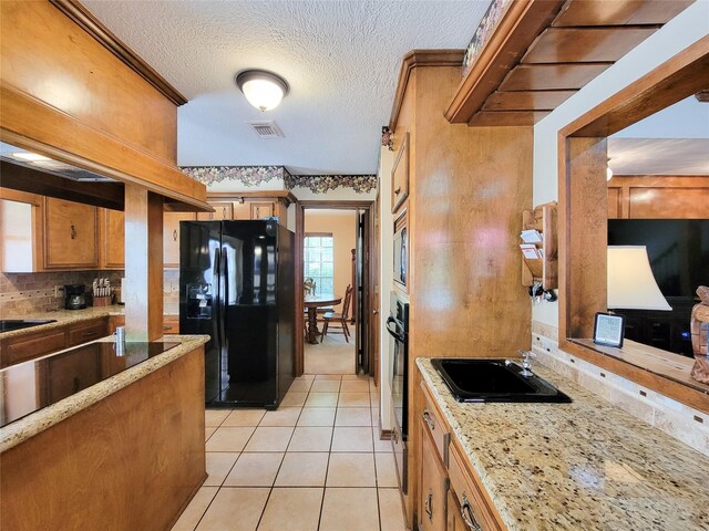 14926 Carols Way Dr, Houston, TX 77070 - kitchen featuring light tile patterned floors, brown cabinets, black appliances, backsplash, and visible vents