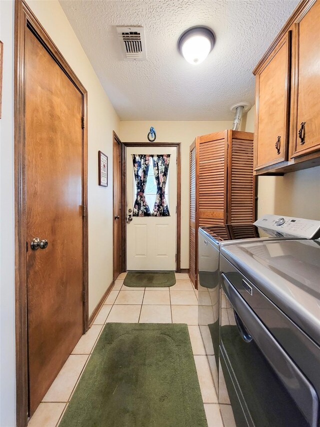 14926 Carols Way Dr, Houston, TX 77070 - clothes washing area with light tile patterned floors, cabinet space, visible vents, a textured ceiling, and washer and clothes dryer