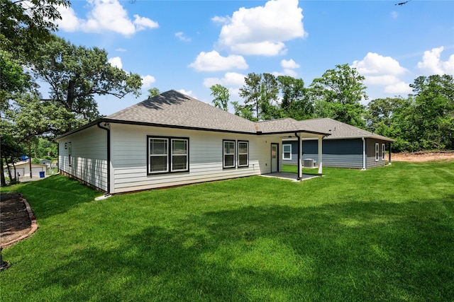 back of house featuring a yard, a shingled roof, and a patio area