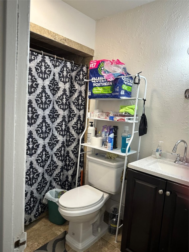 bathroom featuring tile patterned flooring, a shower with shower curtain, toilet, a textured wall, and vanity