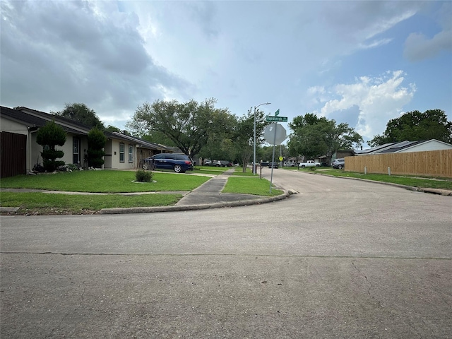 view of road featuring traffic signs, sidewalks, curbs, and street lighting