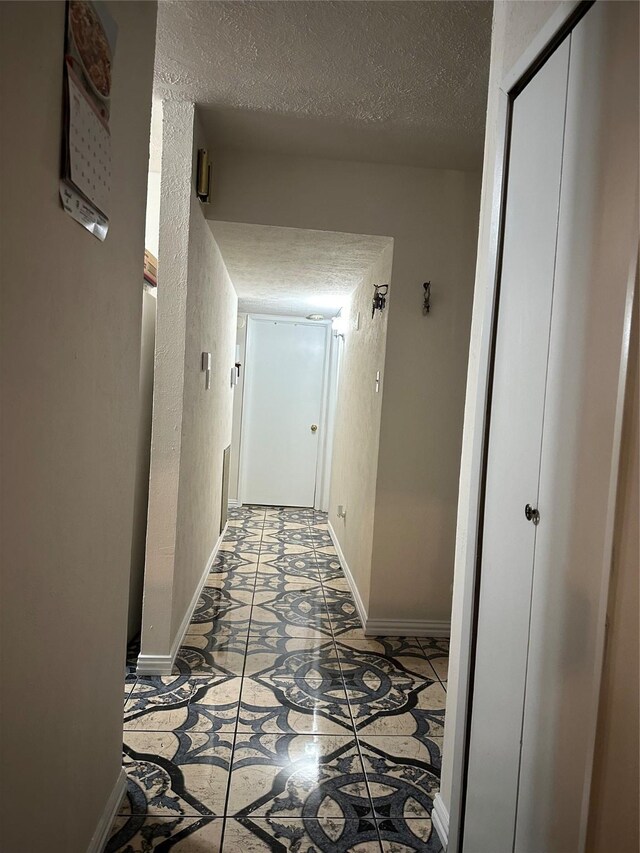 hall featuring baseboards and a textured ceiling