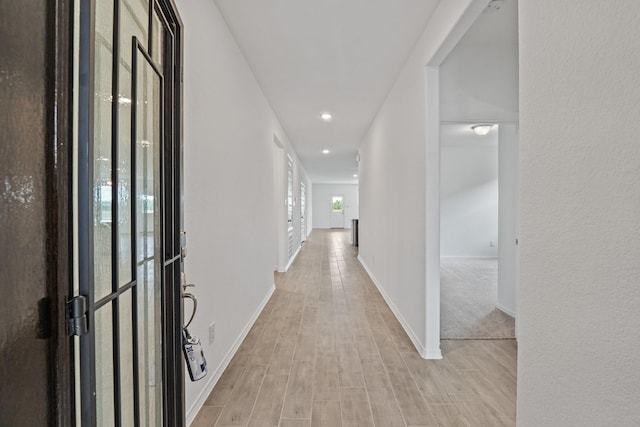 corridor with baseboards, light wood-type flooring, and recessed lighting