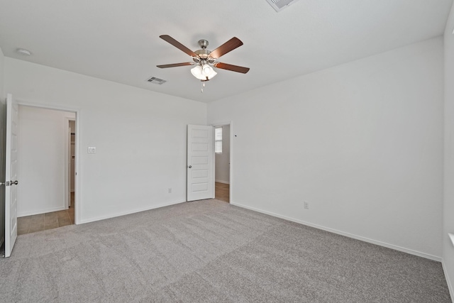 carpeted spare room featuring a ceiling fan, visible vents, and baseboards
