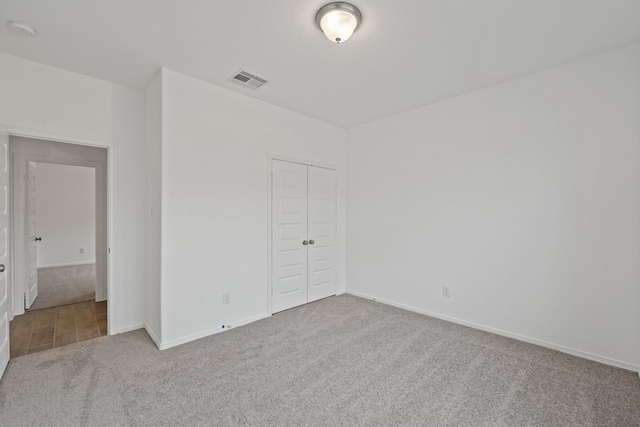 unfurnished bedroom featuring a closet, visible vents, carpet floors, and baseboards