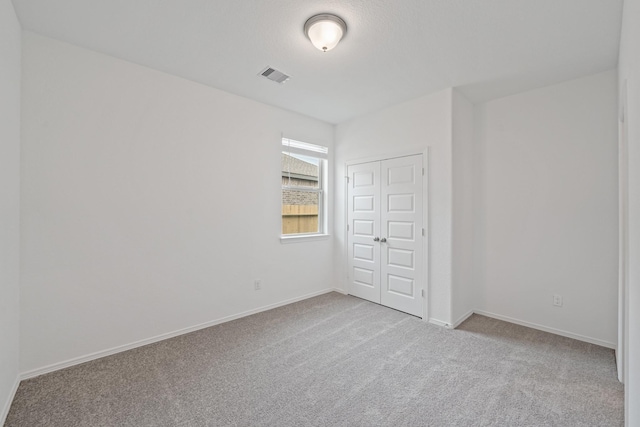 unfurnished bedroom with carpet flooring, a closet, visible vents, and baseboards