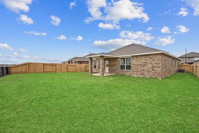 back of house with a fenced backyard, brick siding, a shingled roof, central AC, and a lawn