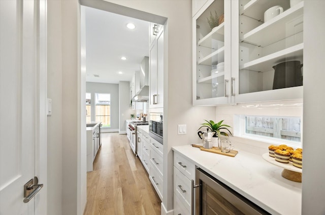 bar featuring wall chimney range hood, high end stainless steel range oven, light wood-style flooring, built in microwave, and recessed lighting