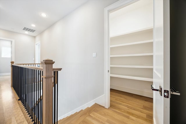 hallway featuring light wood-style flooring, an upstairs landing, visible vents, baseboards, and recessed lighting