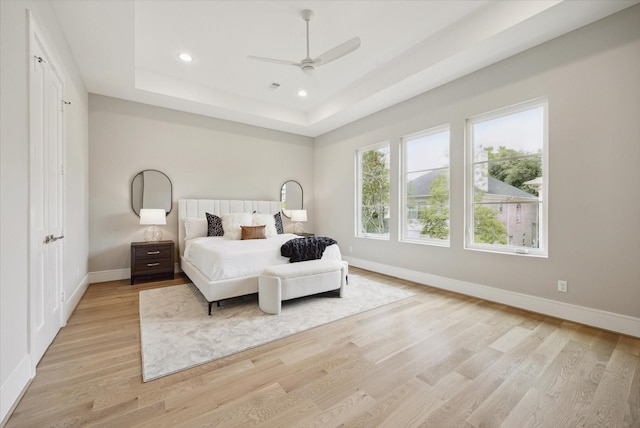 bedroom featuring recessed lighting, light wood-style floors, ceiling fan, baseboards, and a tray ceiling