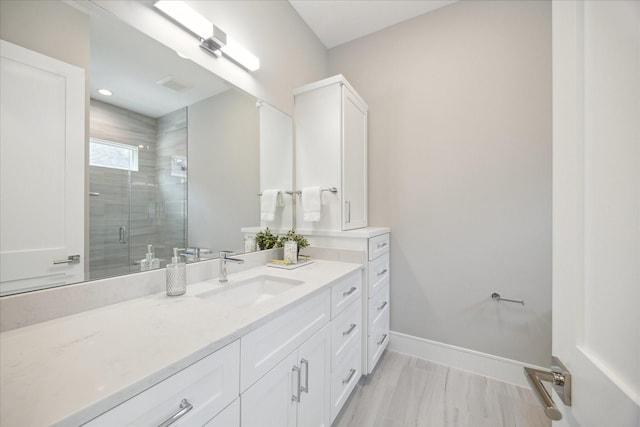 bathroom with baseboards, a shower stall, and vanity