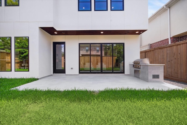 back of property with fence, area for grilling, a patio area, stucco siding, and a yard