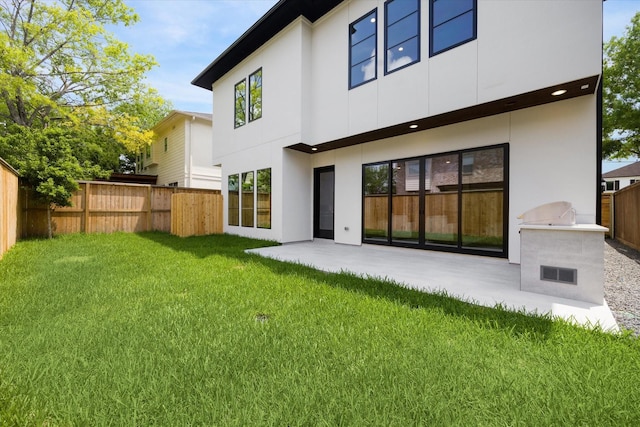 rear view of house with fence, a patio area, stucco siding, and a lawn