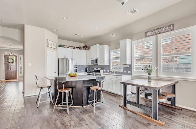 kitchen featuring a center island, a sink, stainless steel appliances, white cabinets, and visible vents