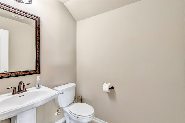 bathroom featuring lofted ceiling, visible vents, toilet, a sink, and baseboards