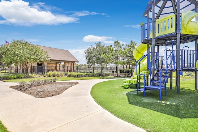 view of community featuring a lawn, fence, and playground community